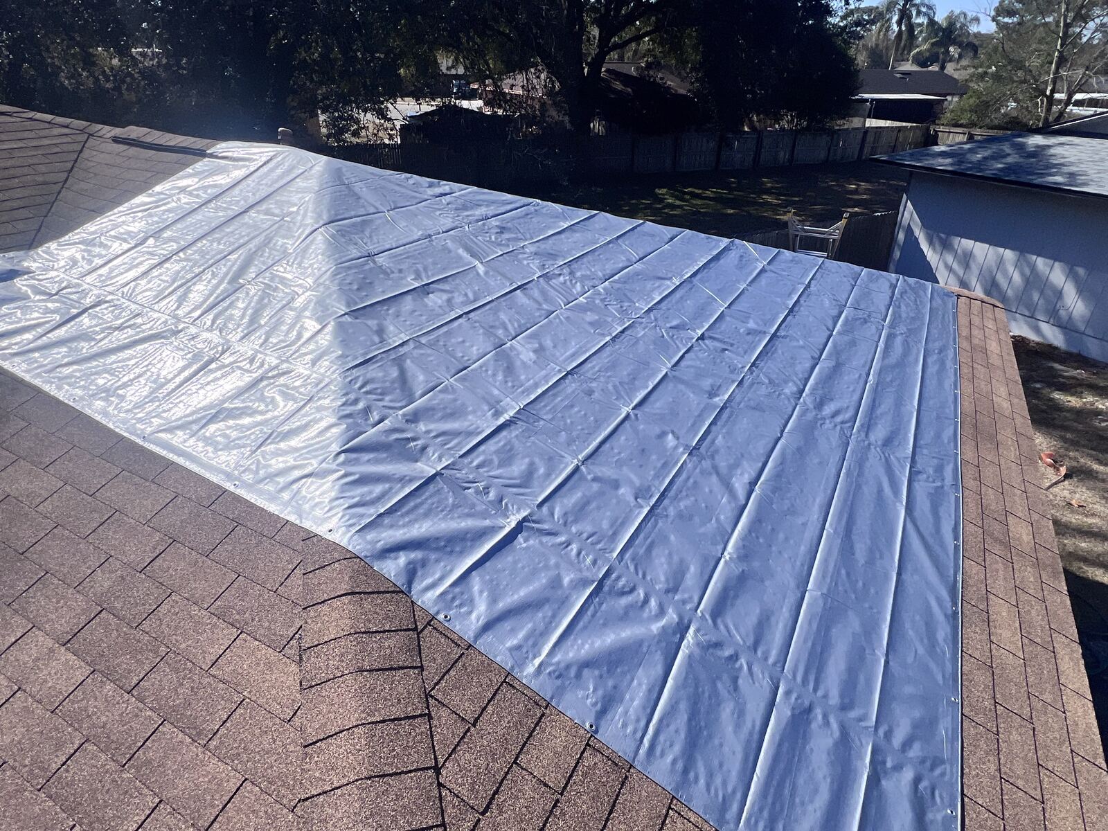 Emergency roof tarp covering ridge before incoming storm